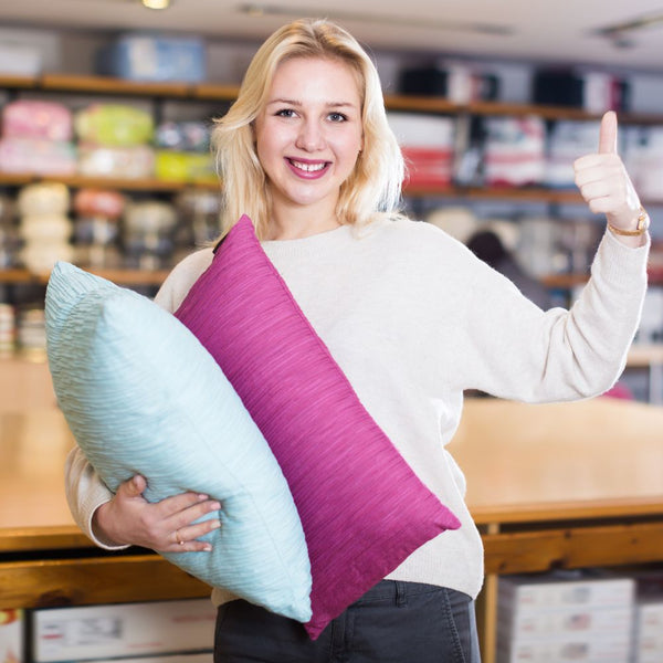 Signora sorridente con due cuscini in mano che simboleggia la guida all'acquisto di un cuscino cervicale