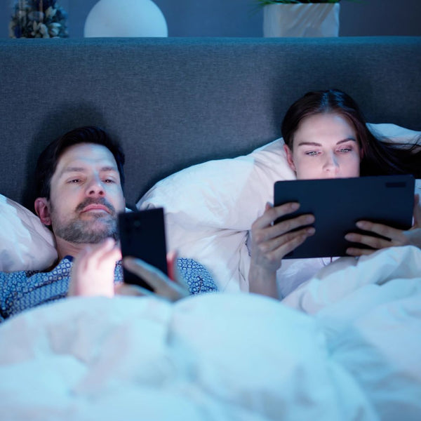 coniugi a letto con cellulare e tablet con conseguente disturbo del sonno